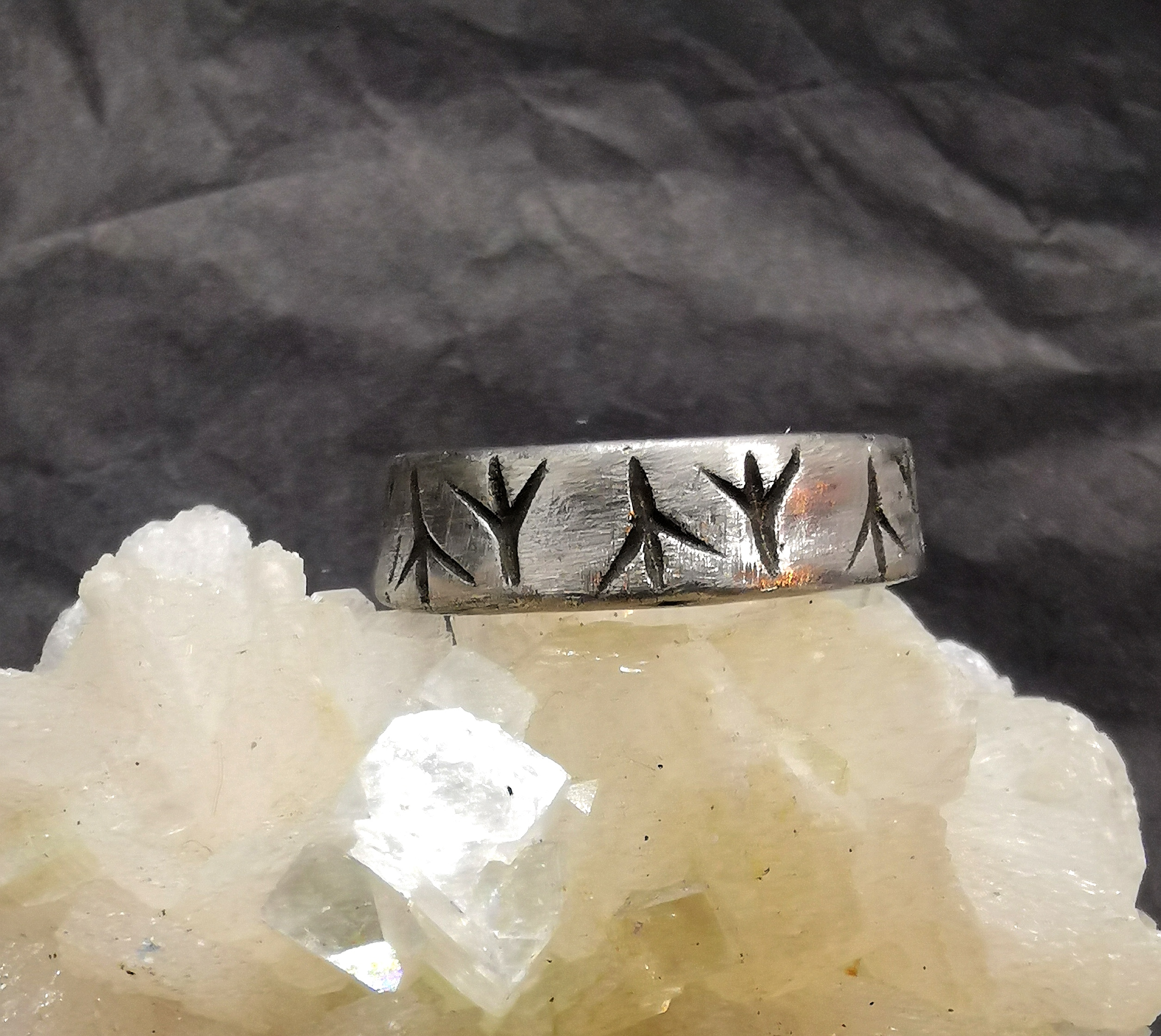 Der Ring aus Stahl besticht durch ins Ringband geschnitzte, leicht geschwärzte Algiz-Runen.